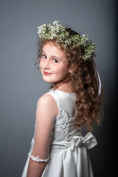 Porträtt av söt liten flicka på vit klänning och krans av första heliga nattvarden. Första nattvardsdagen. Studiofoto — Stockfoto
