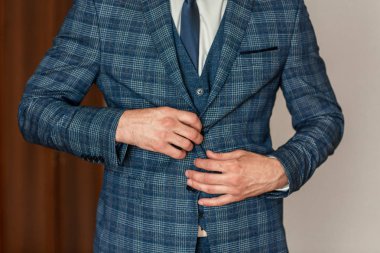 Zarif, özel yapım, pahalı takım elbiseli bir adam arka planda poz veriyor. Damat giyiniyor ve düğün için hazırlanıyor.