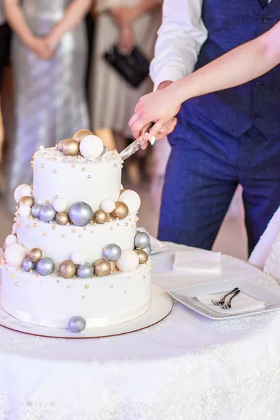 Noiva e um noivo está cortando seu bolo de casamento rústico no banquete de casamento. As mãos cortaram o bolo — Fotografia de Stock