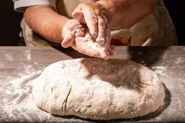 Hands of granny kneads dough. 80 years old woman hands kneading dough. Grandmother dough molding on table. homemade baking. Pastry and cookery.