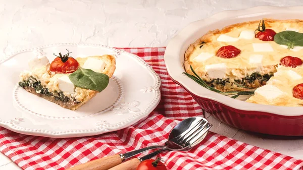Vegetarian spinach pie or tart with feta cheese on a light background. Piece of pie with green stuffed spinach, eggs and cheese.