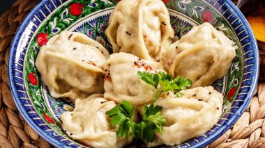 Özbek, Orta Asya tarzında beyaz çiçekli mavi bir seramik tabakta kaynamış Manti veya manty hazırladı.
