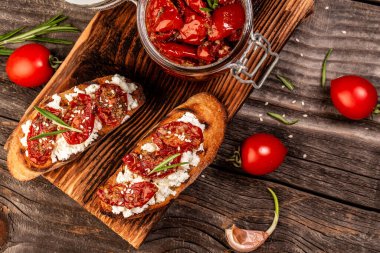 Lezzetli İtalyan mezeleri ya da kızarmış baget, keçi peyniri, güneşte kurutulmuş domates, sarımsak ve kekik dilimleri üzerinde bruschetta. Kapat..