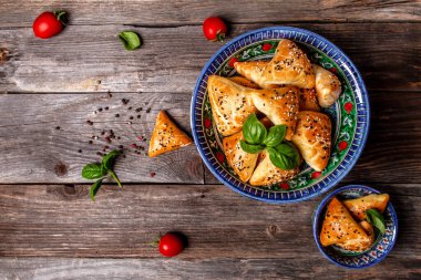 Uzbek national dish samosa. Indian samosas baked pastry with savoury filling, popular Indian snacks, served in bowl with spices on rustic background, top view.