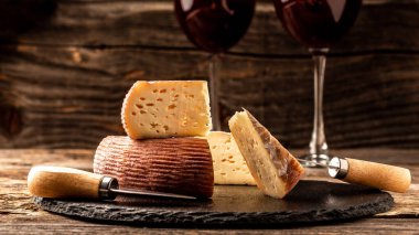 Aperatifli kırmızı şarap, ahşap masada peynir dilimleri..