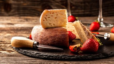 Çilekli Radaer peyniri, peynir bıçağı, keçi sütünden yapılmış üçgen kesim. Yakın plan. Metin için pankart menüsü tarifi yeri.