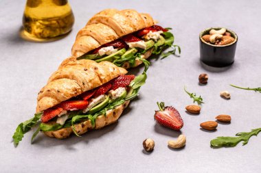 Doldurulmuş iki kruvasan. Roka salatası, çilek ve peynir peyniri, camembert peyniri. en üstteki görünüm.