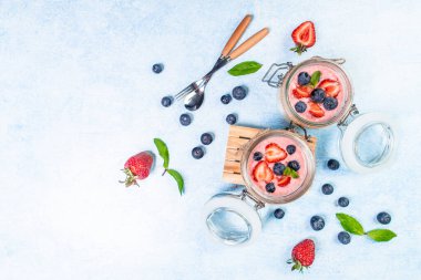 İki beyaz kasede servis edilen taze çilek böğürtlenli Yunan yoğurdu veya kremalı tatlı. Metin ve üst görünüm için pankart menüsü tarifi yeri.