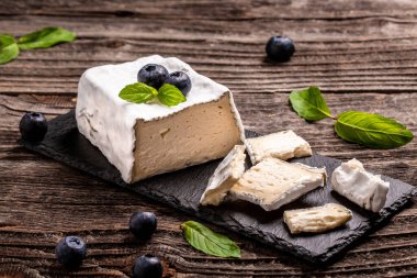 Taze Valencay peyniri. Valencay keçi peyniri, kayrak tahtada böğürtlen ve kırsal bir arka plan..