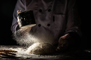 Elek kevgir un, hamuru dövmek için un ve iş yerinin yatay çekimi. Havaya uçan beyaz un. Yiyecek konsepti