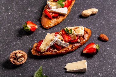 Yaz atıştırması. Lezzetli ev yapımıyla yapılmış, jambonlu çilekli ciabatta, peynirli camembert fındığı ve bal. Yemek tarifi geçmişi. Metin için boşluk. en üstteki görünüm.