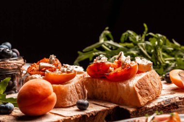 Yumuşak lacivert peynirli lezzetli tost, taze sulu şeftali, ahşap tahtada yabanmersini ve bal. Sağlıklı yaz aperatifleri ya da atıştırmalıklar, metin için yer.