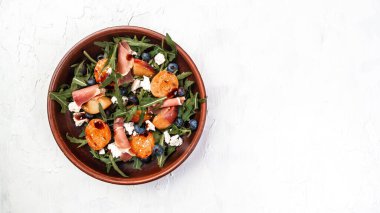 Mavi peynirli, şeftalili, jambonlu ve roka arkaplanlı gurme salatası. Pankart. Üst görünüm.