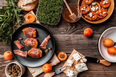 Peynir, şeftali, prosciutto dilimleri ve kapari ile lezzetli atıştırmalıklar, mikroyeşil, ahşap masa, yukarıdan görüş, metin için yer.