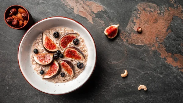 Lezzetli ve sağlıklı yulaf ezmesi, incir, yabanmersini ve chia çekirdeği. Sağlıklı kahvaltı glüten, laktozsuz, fitness yemeği. Uzun pankart biçimi, üst görünüm.