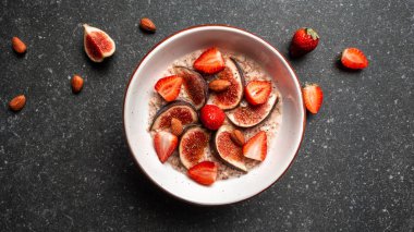 Lezzetli yulaf ezmesi, incir parçalarıyla süslenmiş, bir kasede çilek ve chia tohumları, sağlıklı kahvaltı glüten, laktozsuz, fitness yiyeceği. Uzun pankart biçimi, üst görünüm.