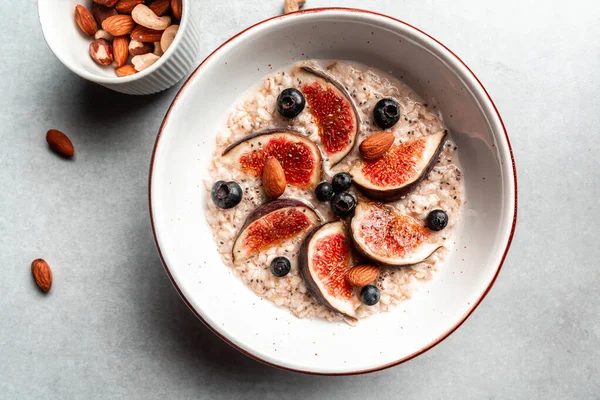 İncirli yulaf ezmesi, yabanmersini, fındık, gri arka planda chia tohumu. Sağlıklı Kahvaltı. Tatlı yemek tatlısı. Üst Manzara. Düz Yat.