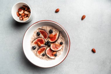 Böğürtlenli yulaf ezmesi, fındık ve bal. Kahvaltı: Yulaf ezmesi, yaban mersini ve incir hafif arka planda, glüten, laktoz yok, fitness yemeği, üst manzara.