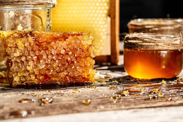 Honey background. Sweet honey in the comb, glass jar with honey on wooden background. Beekeeping concept. Copy space.