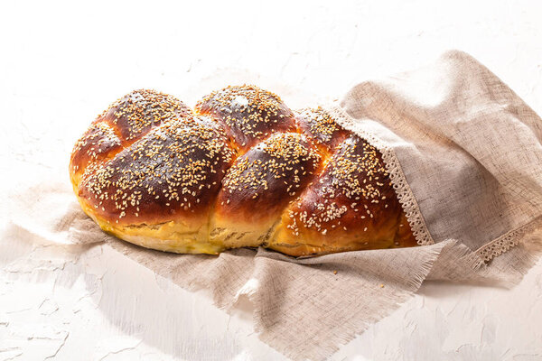 fresh challah jewish bread with sesame on a white background loaves for Shabbat. passover holiday and shabbat concept.