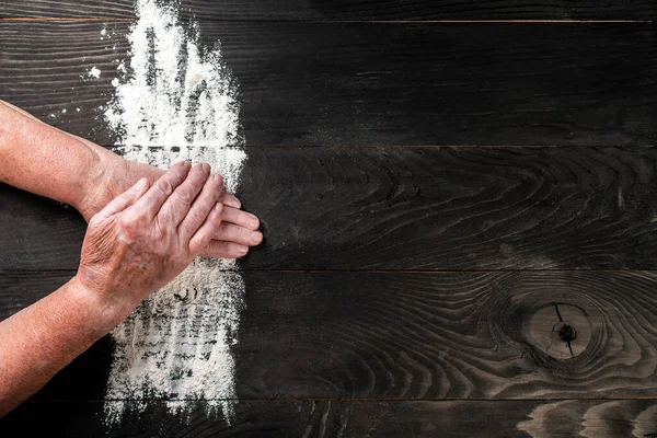 Yaşlı bir kadının elleri, un şeklinde bir kalple siyah masa üzerinde un, yemek tarifi menüsü geçmişi. mesaj için yer. Uzun pankart biçimi.