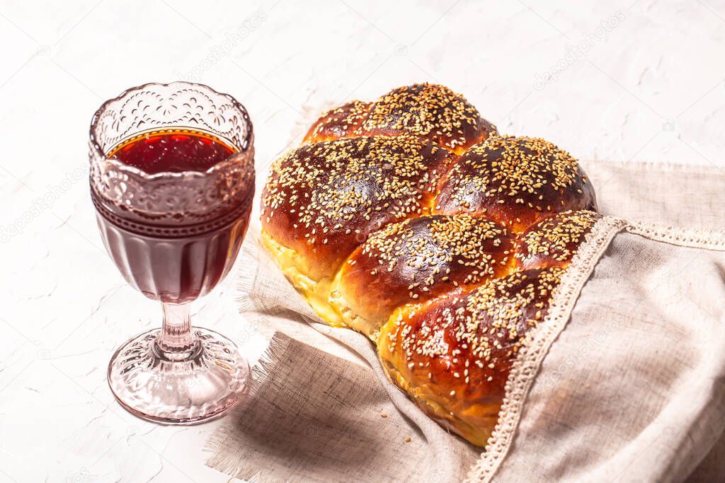 Shabbat or Sabbath kiddush ceremony. The concept of oriental cuisine. National Israel sweet fresh loaf of challah bread, glass of red kosher wine.