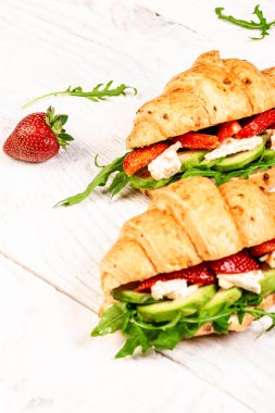 Peynirli kruvasanla taze sandviç, çilek, ıspanak. Hafif arka planda lezzetli kahvaltı ya da atıştırmalık, uzun afiş biçimi.