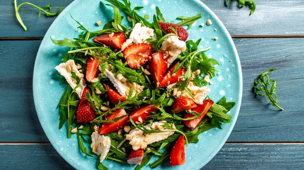 Close up salad with arugula, strawberries and cheese brie, camembert. Healthy food diet food concept. recipe background.