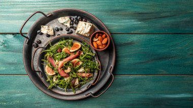 İncirli Prosciutto di Parma salatası, mavi peynir ve roka. Sağlıklı gıda konsepti.