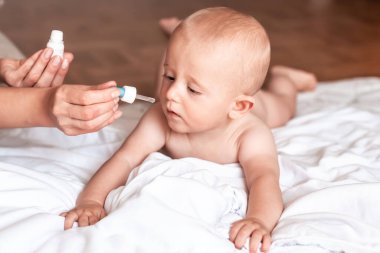 Annesi oğlu için burun damlası damlatıyor. Solunum sintaktik virüsü. Sağlık hizmeti kavramı,