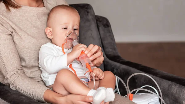 Bebek solunum terapisi görüyor. Evde bir nebulizörün maskesini tutan el. Astım ya da zatürree belirtileri solunum sintaktik virüsünden kaynaklanıyor. Sağlık hizmeti kavramı.