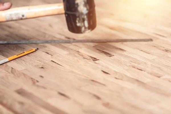 Carpenter on work laying laminate or parquet flooring use a rubber mallet, Worker installing wooden laminate flooring.