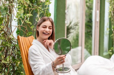 Cilt bakımı. Güzel yüzlü kadın sağlıklı yüz portresine dokunuyor. Güzel, gülümseyen, beyaz, doğal makyajlı genç bir kadın model, parlayan nemli cilde dokunuyor. Sağlık kaplıcası.