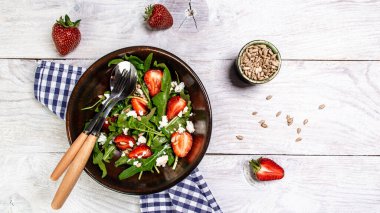 Beslenme menüsü. Sebze, çilek, roka, ricotta ve tohumdan oluşan sağlıklı vejetaryen salatası. Düz yatıyordu. Üst görünüm.