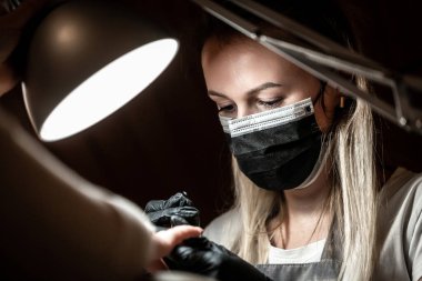 Usta, kuaförde manikür yaparken ojeyi çıkarmak için elektrikli makine kullanıyor. Donanım manikürü. Karantina süresi. Küçük işletme ve covid-19, koronavirüs..