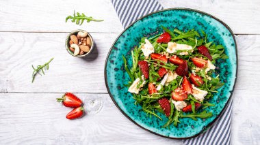 Taze çilek salatası roka, çilek ve peynir peyniri, camembert peyniri. Keto diyet yemekli tabak. Nefis bir kahvaltı ya da hafif bir arka planda atıştırmalık..