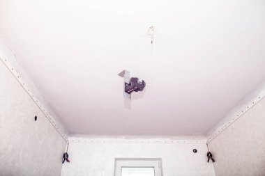 Lazer seviyesinde bir alet. Odaya askıya alınmış tavanların kurulumu.