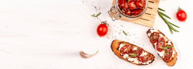 sandwich with goat cheese, sun-dried tomatoes and garlic, oregano, olive oil on a light table. space for text. top view. Long banner format. clipart