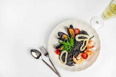 Beyaz tabakta deniz ürünleri ve roka ile siyah spagetti. Üst Manzara. Boşluğu kopyala.