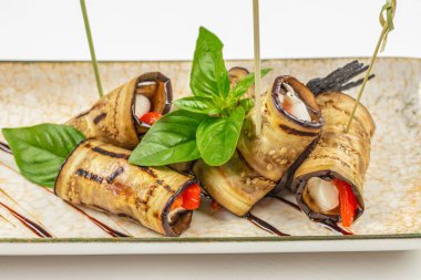 Peynirli ızgara patlıcan rulosu ve seramik tabakta kırmızı biber..