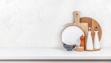 Mutfak tabakları ve tahta kesme tahtaları beyaz masa arkasında. Uzun afiş biçimi. Boşluğu kopyala.