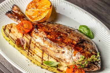 Beyaz tabakta limonlu sebzeli dorado balığı ızgarası. en üstteki görünüm.