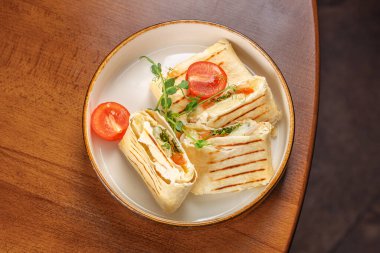 Izgara lavaş ambalajı, sebze ve sosla birlikte beyaz bir tabakta fotokopi alanı ile..