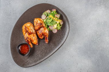 Koyu bir tabakta yeşil salata ve baharatlı sos ile servis edilen kızarmış tavuk, fotokopi alanı ile üst manzara..