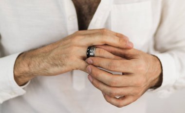 Beyaz adamın elleri değerli taşlarla iki yüzük takıyor. Erkekler için mücevherler. Nişan yüzüğü..