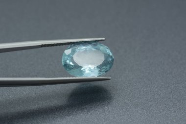 Gri metalik arkaplana sıkıştırılmış akuamarin değerli taşının makro görüntüsü