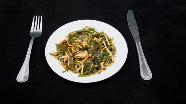 Sea kale in a plate on a black background