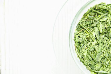 Açık arkaplanda şeffaf bir fincanda yeşil çay