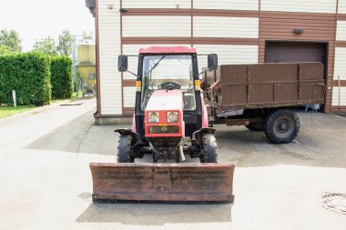 Kar küreme aracı, karavanı olan küçük bir traktör sokakta duruyor.