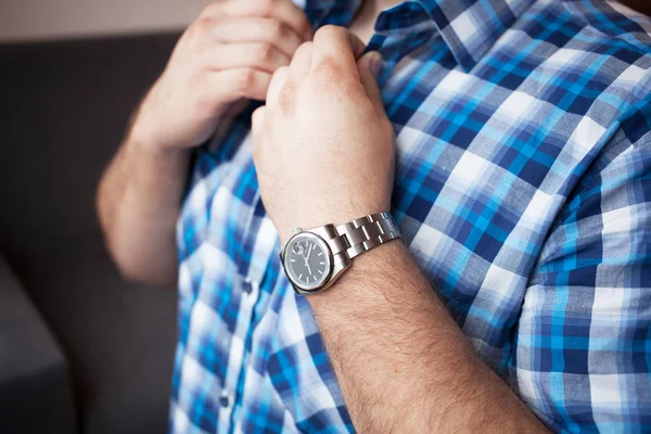 sturdy man in a blue plaid shirt with a short sleeve and a watch on his wrist buttons collar